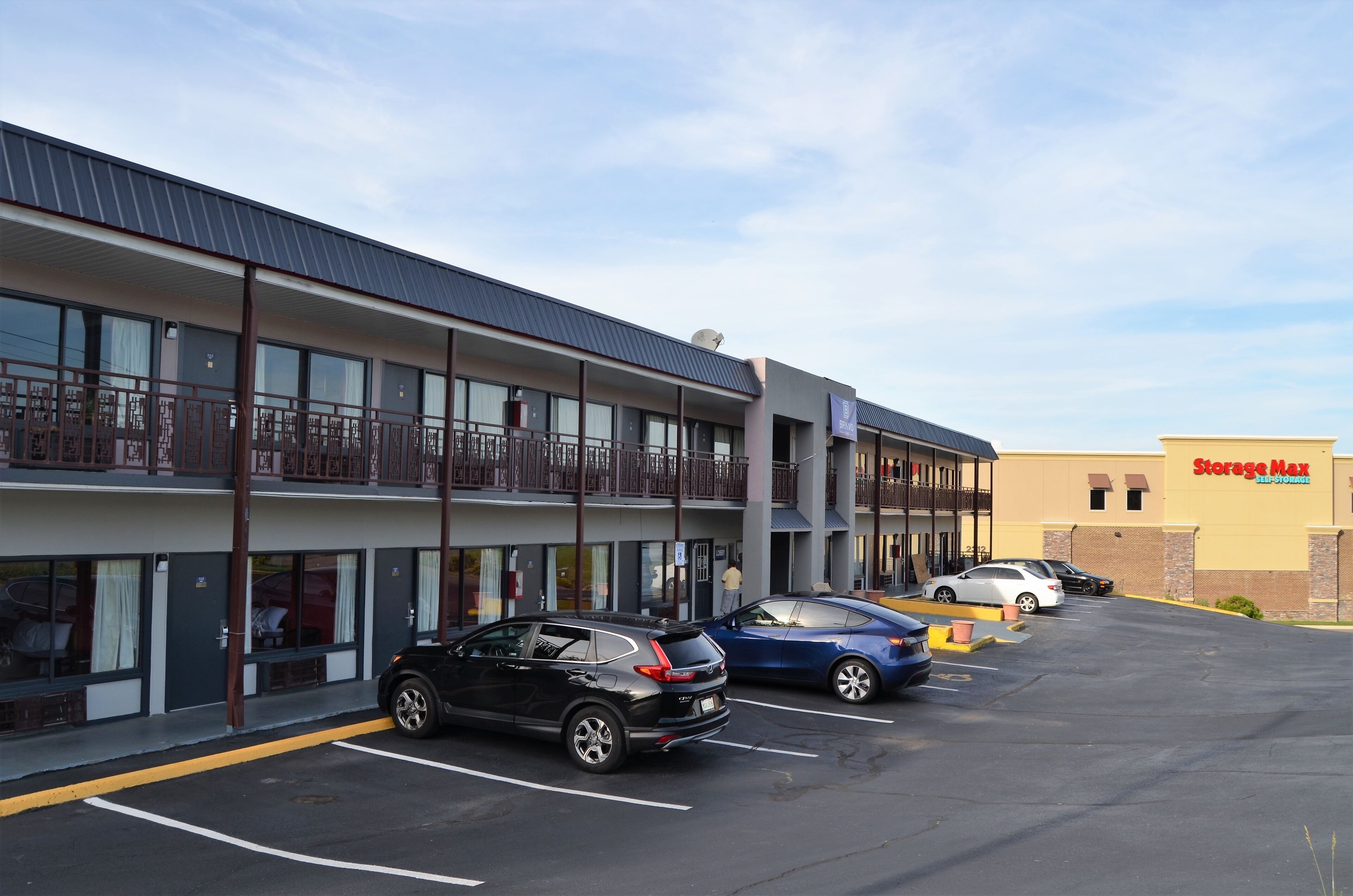 A hotel with a parking lot, a balcony, and a Storage Max store in the background.