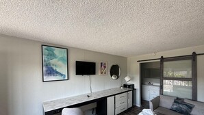 A modern bedroom with a bed, a desk, a chair, a TV, and a window. - I-26 Inn (Johnson City)