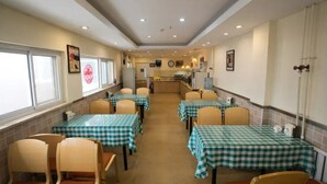 A dining area with checkered tablecloths, beige chairs, and a kitchen in the background. - Home Inn Hotel Beijing Capital Airport No.3 Terminal (Beijing)