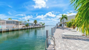 A waterfront walkway with lounge chairs and a poolside area. - Seas The Day in Cudjoe Key (Cudjoe Key)
