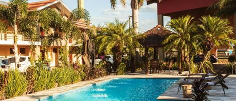 Un hotel con piscina rodeada de palmeras y sillas de descanso.