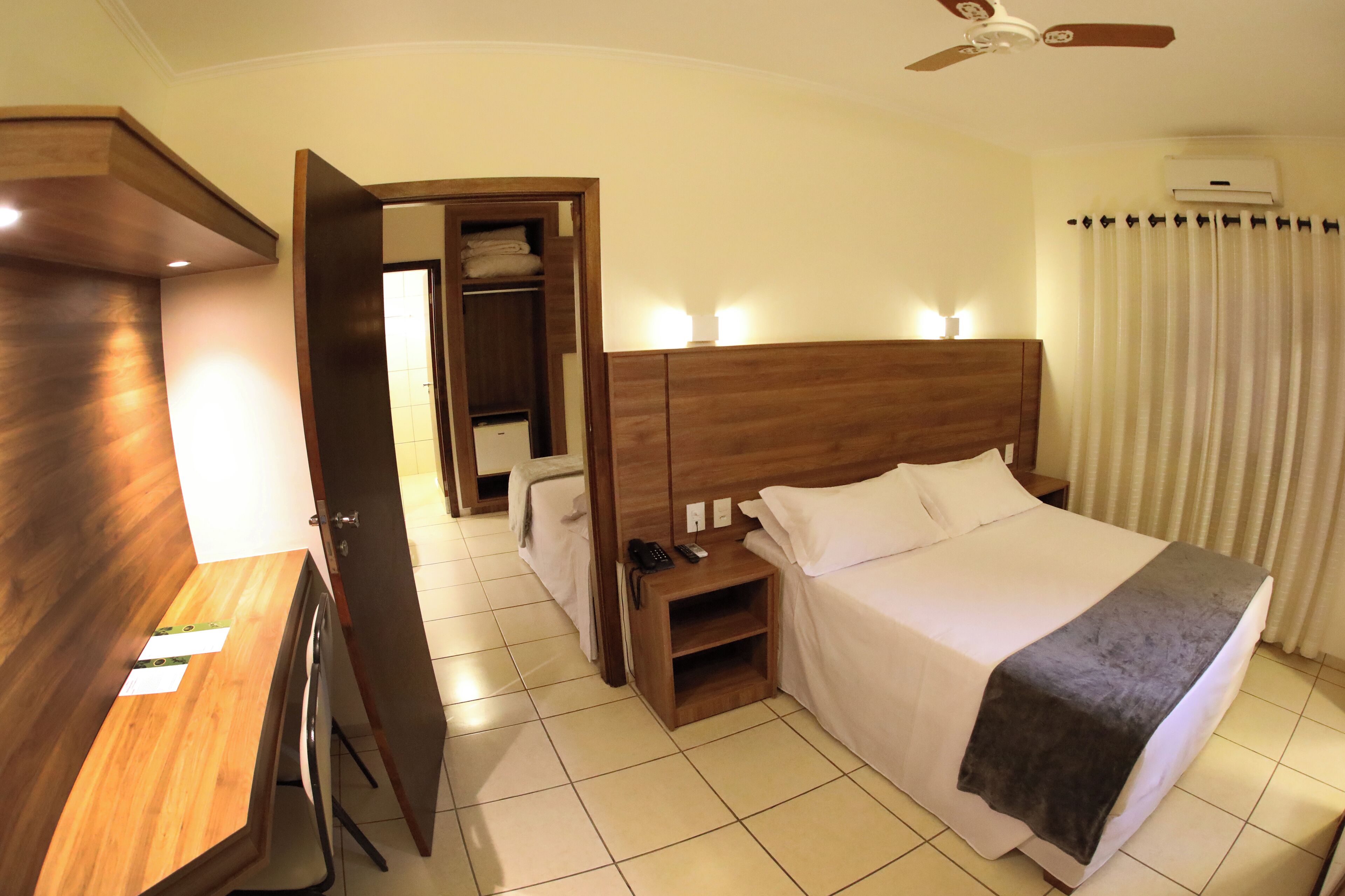 A hotel room with a wooden bed, bedside table, and a wardrobe.