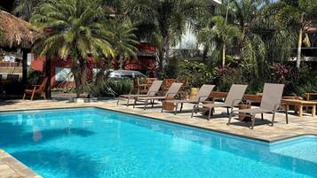 Una piscina al aire libre, sillones reclinables de piscina