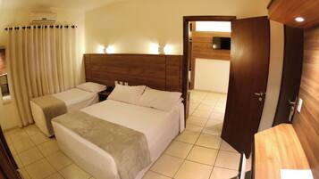 Una habitación de hotel con dos camas, cabecero de madera, ventilador de techo y suelo de baldosas.