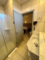 Un baño de hotel con lavamanos, secador de pelo y un perchero para toallas.