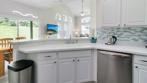 A modern kitchen with white cabinetry, a stainless steel dishwasher, and a tiled backsplash.