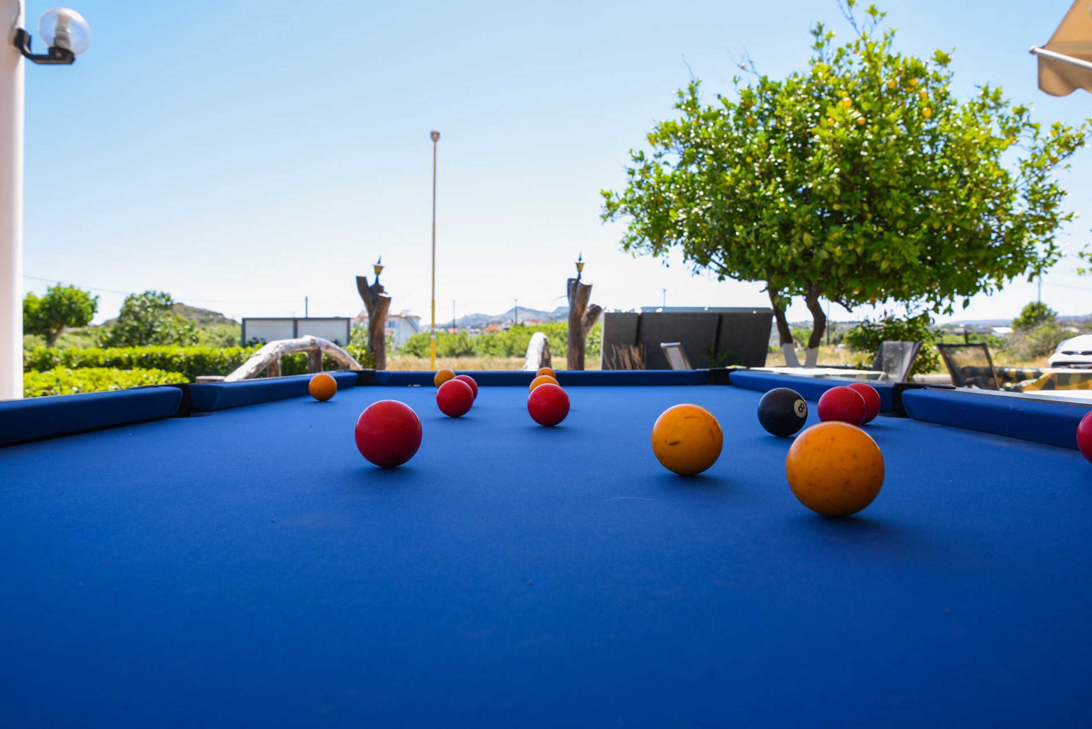 A pool table with balls, a lamp, and a tree in the background.