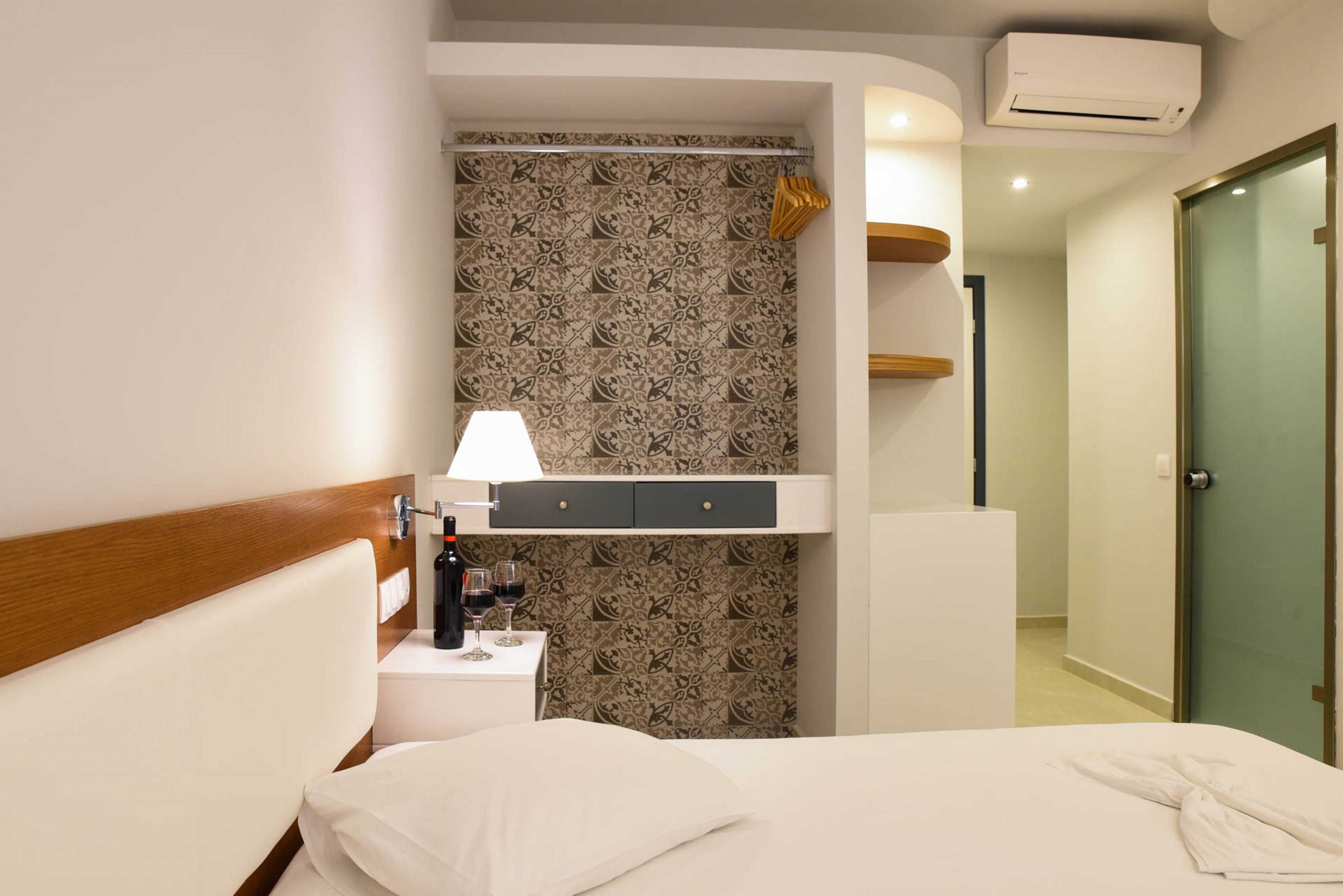 Une chambre d’hôtel avec un lit, une table de chevet, une lampe et un mur décoré d’un motif.