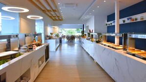 Un espace buffet moderne doté de plans de travail en marbre, d’un long comptoir et d’un espace de restauration central avec des tables et des chaises.