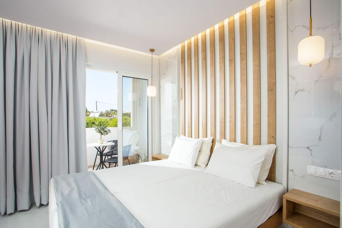 Una habitación de hotel moderna con una cama grande, cabecera de madera y vistas al exterior.