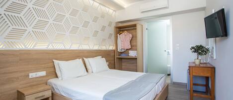 A modern bedroom with a wooden headboard, a bed with white linens, a bedside table, a built-in wardrobe, and a TV mounted on the wall.