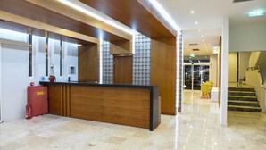 Een modern receptiegebied met een houten receptiebalie, een brandblusser en een decoratieve wand.