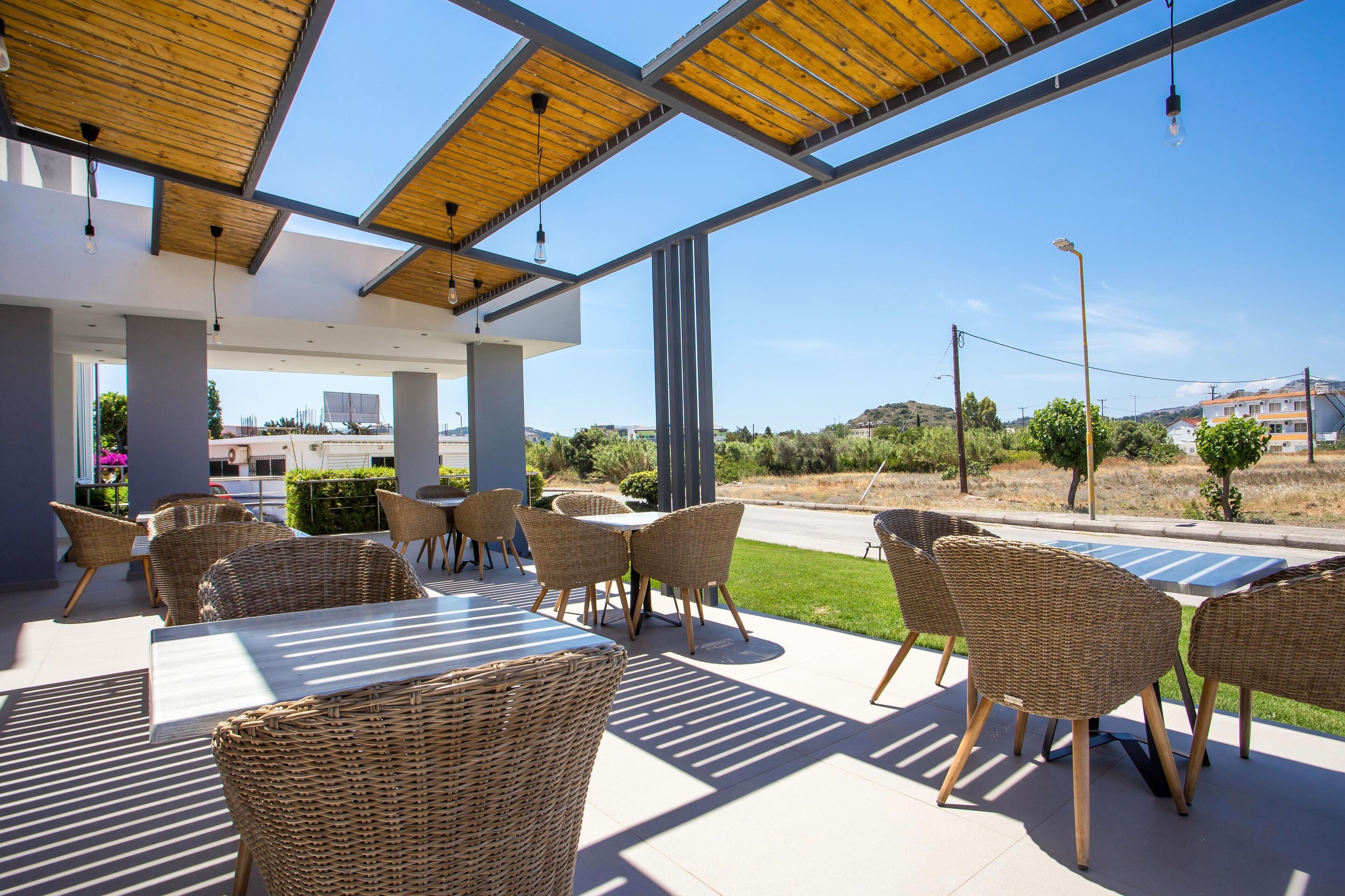 An outdoor patio area with wicker furniture and a modern design, featuring large windows and a view of the surrounding landscape.