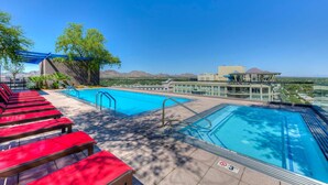 A rooftop pool with red lounge chairs, a blue pergola, and a view of mountains. - Condo magnifico in the heart of the Biltmore (Phoenix)
