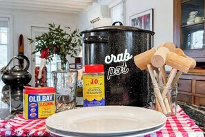 A kitchen counter with a pot labeled "crab pot," a can of Old Bay seasoning, a jar, and wooden utensils.