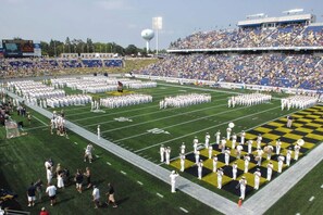 A football field with marching bands and a crowd in the stands.