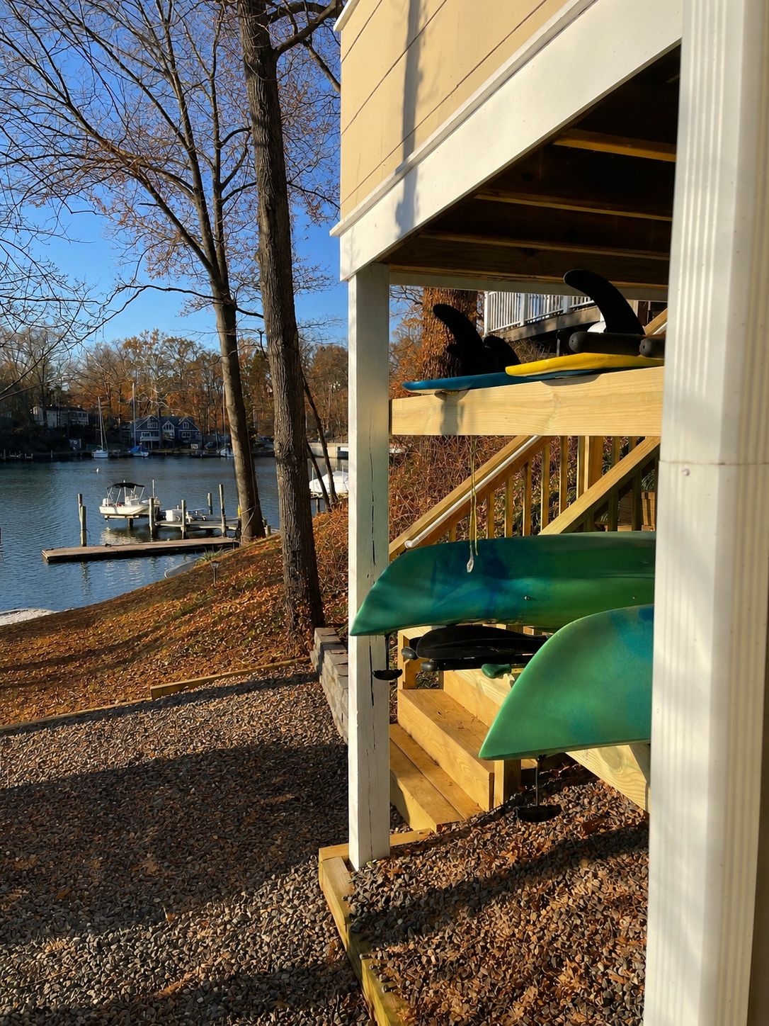 Une terrasse en bois avec des kayaks et un quai au bord d’un lac.
