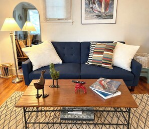 A living room with a blue sofa, two lamps, a framed picture, and a coffee table with decorative items. - Your Annapolis Waterfront retreat for a weekend or any-day getaway! (Annapolis)