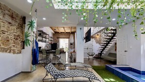 A spacious living area with a modern design, featuring a large sofa, a dining table, and a staircase leading to another level. - Fun House, Pool & Rooftop, Best Location Getsemani (Cartagena)