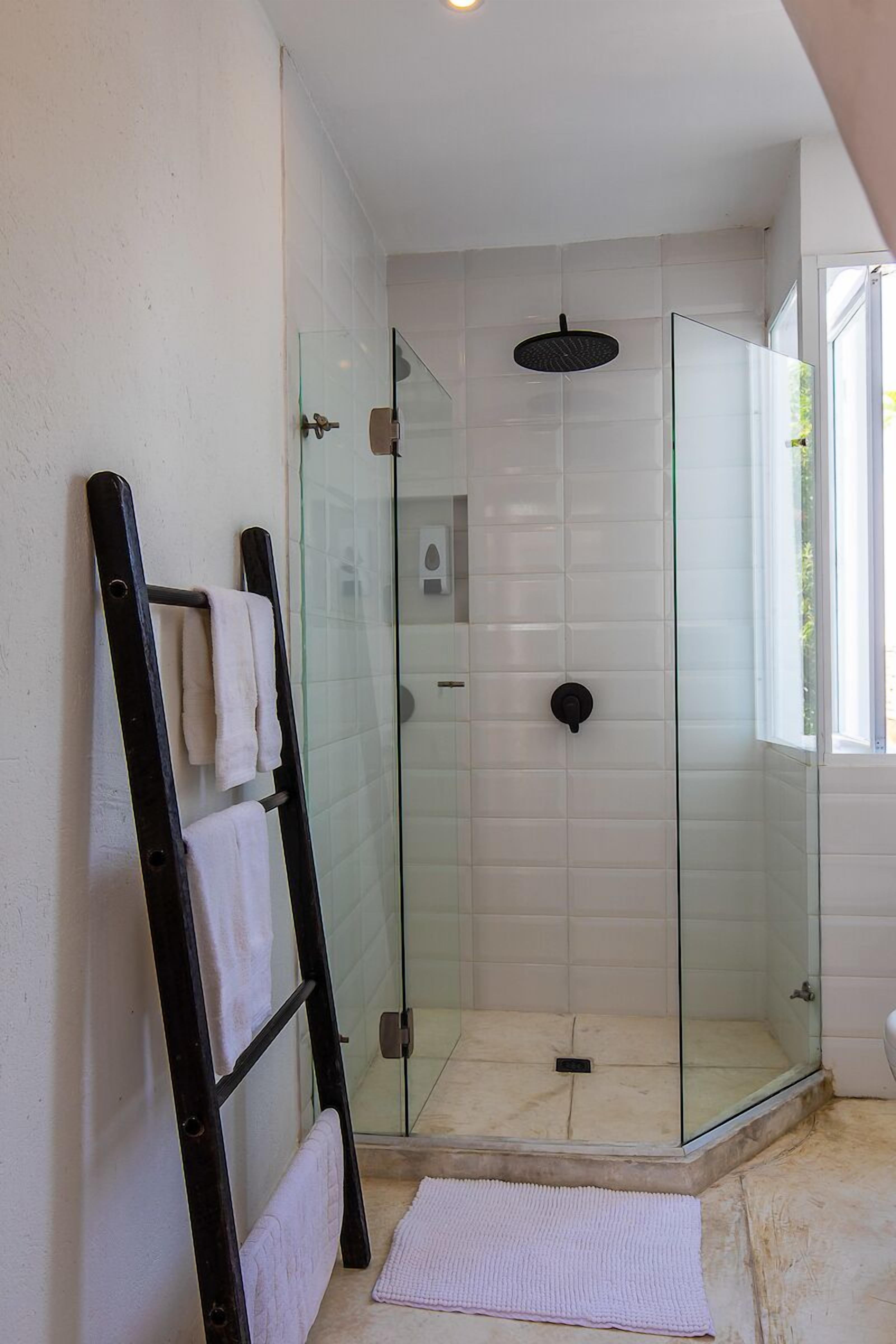 A glass-enclosed shower with a black showerhead, a glass door, and a towel rack with towels.