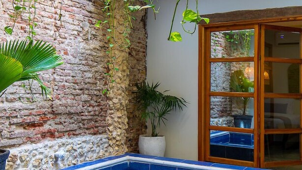 A swimming pool with blue tiles, surrounded by a brick wall and greenery. - Fun House, Pool & Rooftop, Best Location Getsemani (Cartagena)
