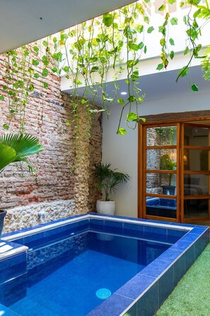 A swimming pool with blue tiles, surrounded by a brick wall and greenery. - Fun House, Pool & Rooftop, Best Location Getsemani (Cartagena)