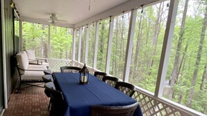 A covered patio with a table set for dining, chairs, and a ceiling fan. - Shangri-La Cabin your mountain top Utopia (Blairsville)
