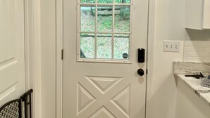 A white door with a window, a sign above it that reads "be our GUEST", and a kitchen area with white cabinets and a marble countertop. - Shangri-La Cabin your mountain top Utopia (Blairsville)