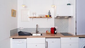 A compact kitchen with a dishwasher, a coffee machine, and a built-in oven.