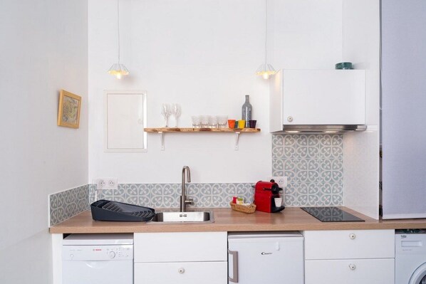 Una cocina compacta equipada con lavavajillas, cafetera y horno empotrado.