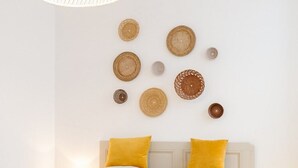 A bedroom with a bed, a hanging light fixture, and wall decor.