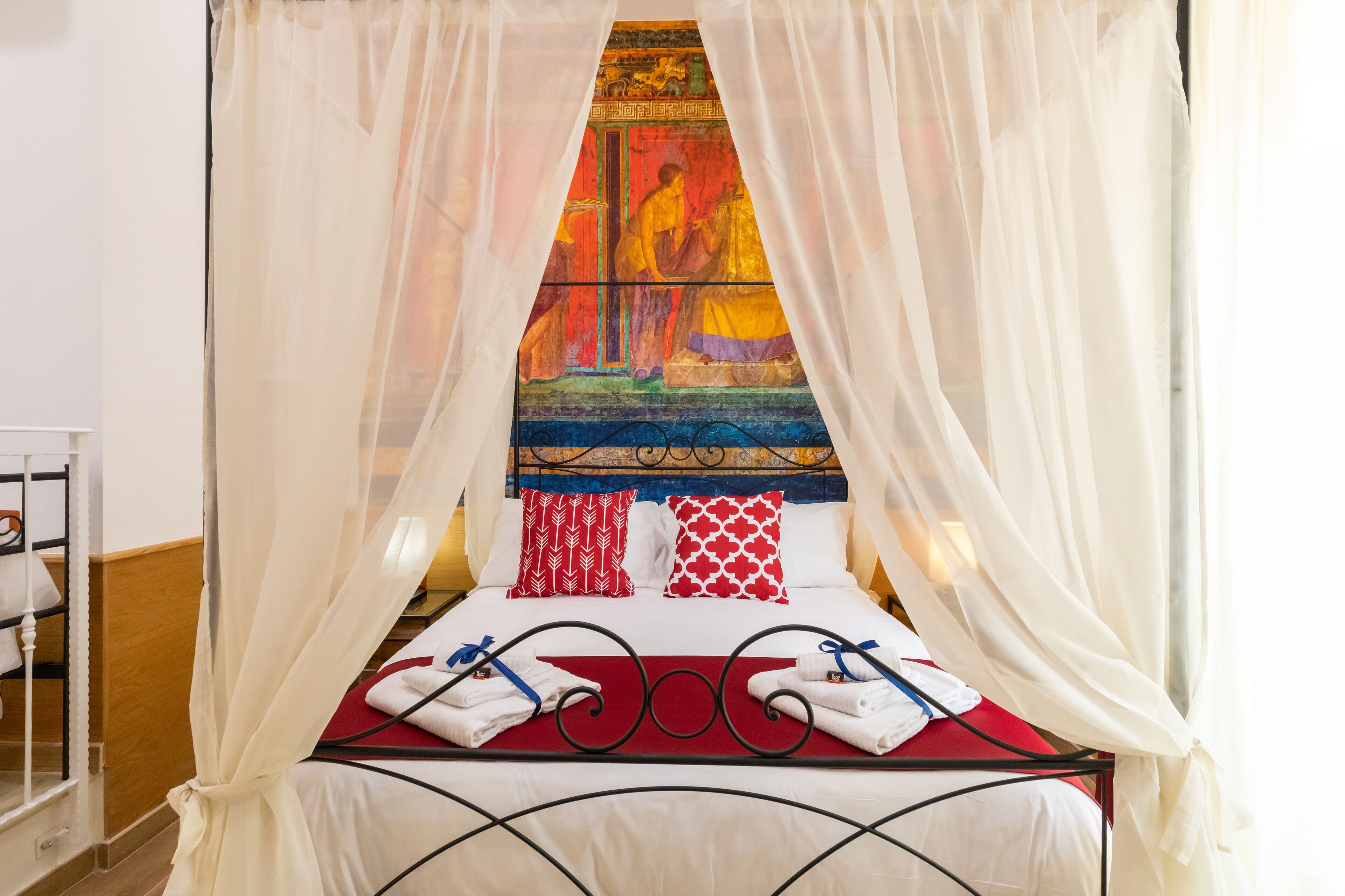 Un letto a baldacchino, con cuscini rossi e bianchi e una coperta rossa.