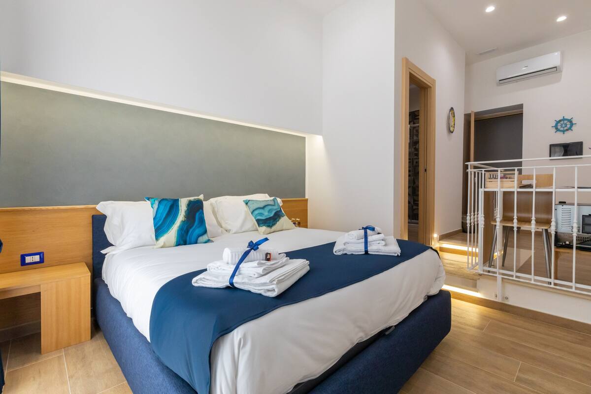 A hotel room with a bed, a nightstand, a desk, and a chair.