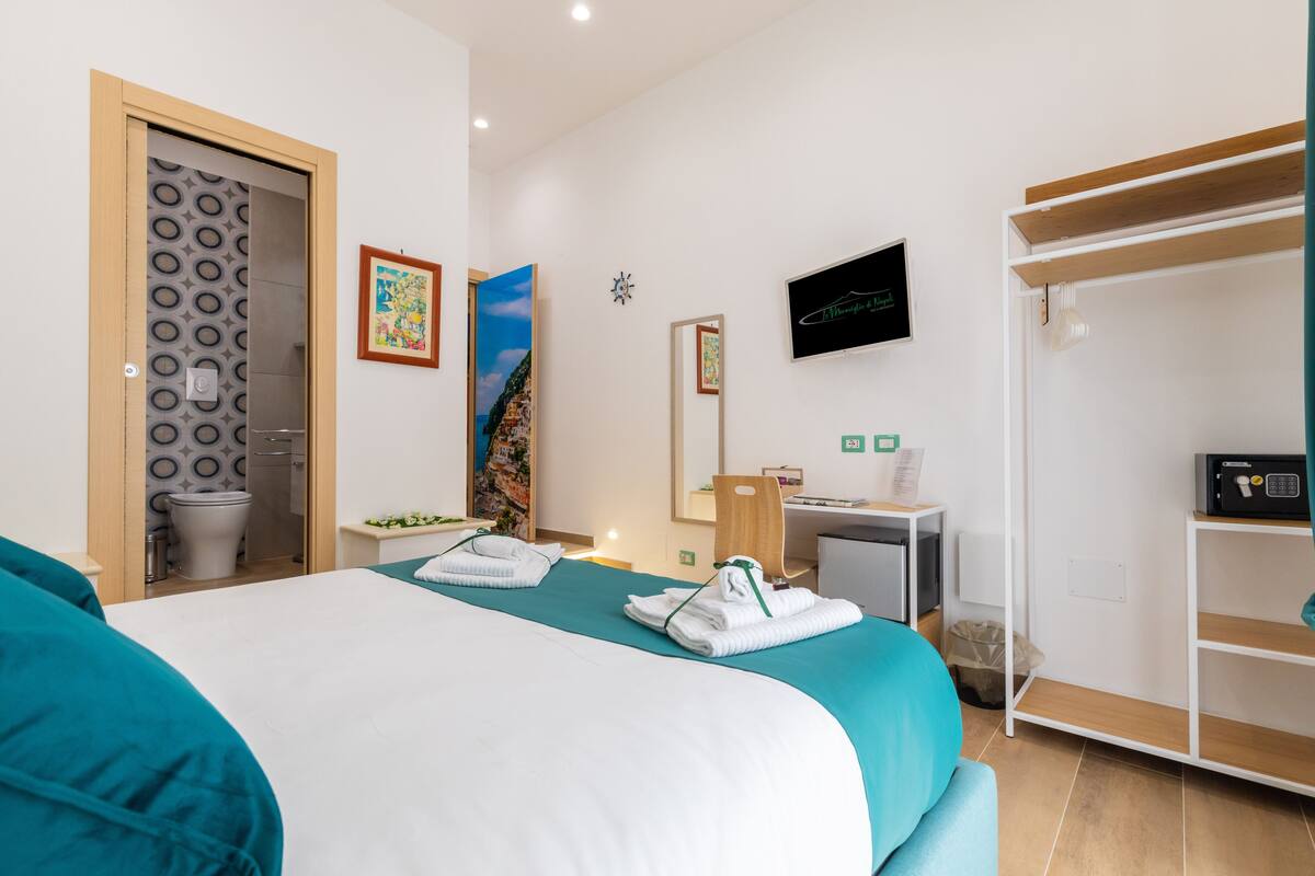 A hotel room with a bed, a desk, a TV, and a wardrobe.