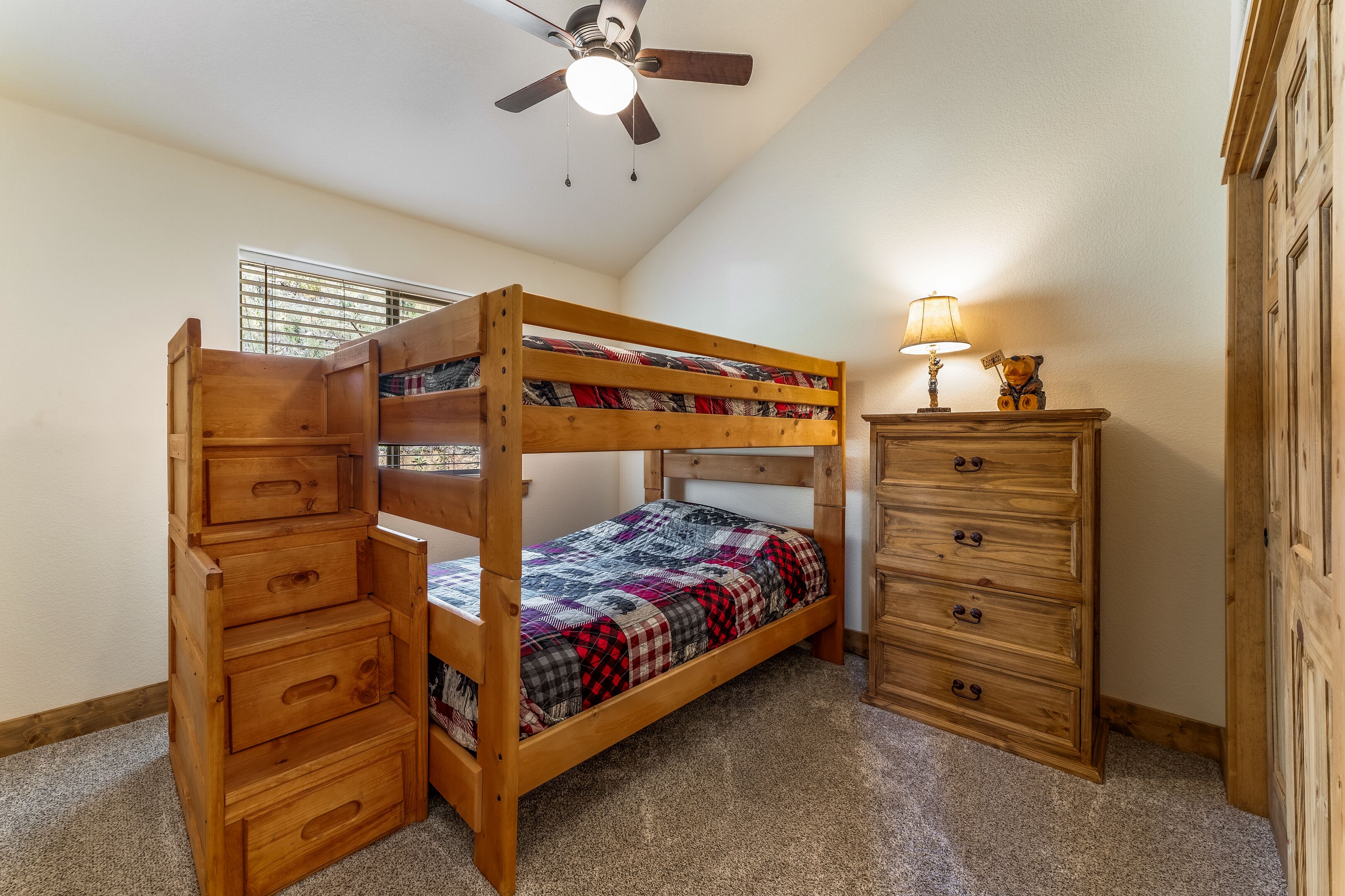 Ein Schlafzimmer mit Etagenbett, Schubladen, Kommode und Deckenventilator.