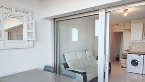 Eine moderne Küche mit Waschmaschine, einem Essbereich inklusive Tisch und Stühlen sowie einer Glastür, die auf einen Balkon führt.