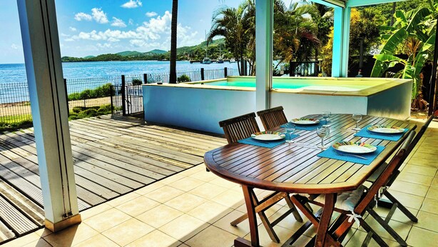 Una mesa de madera preparada para comer, con vista al mar y a las montañas.