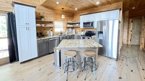 A modern kitchen with wooden cabinetry, stainless steel appliances, and a central island with stools.