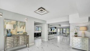 A spacious living area with a marble floor, a large abstract painting, and a modern kitchen in the background. - Welcome to Paradise! 1 mile to beach heated pool! (Hollywood)