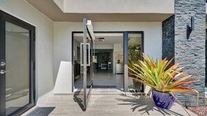 A modern house entrance with a glass door, a potted plant, and a stone wall. - Welcome to Paradise! 1 mile to beach heated pool! (Hollywood)