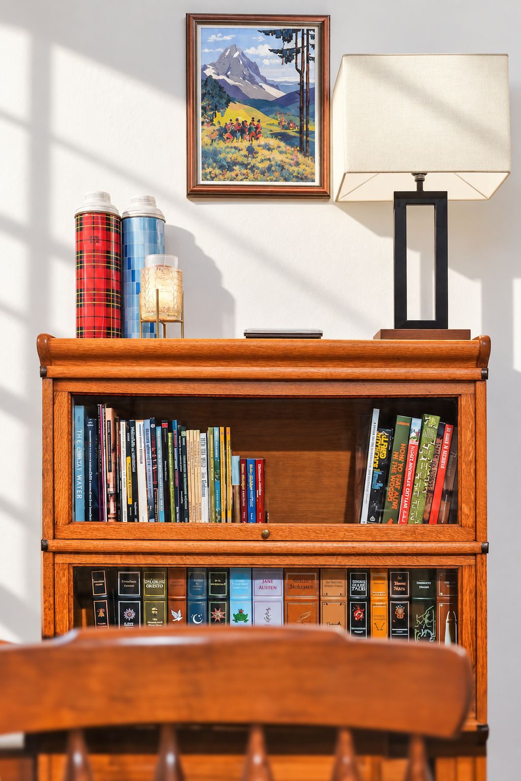 A wooden bookshelf with books, a framed painting, and a lamp on a table.