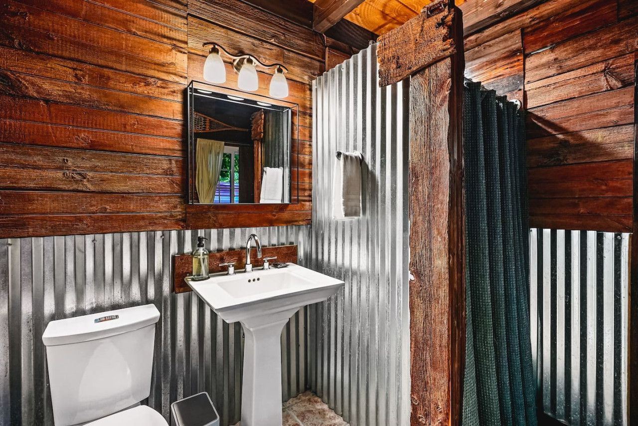 A bathroom with wooden walls, a white sink, and a toilet.