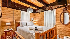 A wooden cabin-style bedroom with a bed, bedside table, lamp, and a hanging light fixture. - Chalet Getaway | Hot tub | Sauna | Firepit (Bellaire)