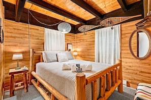 A wooden cabin-style bedroom with a bed, bedside table, lamp, and a hanging light fixture. - Chalet Getaway | Hot tub | Sauna | Firepit (Bellaire)