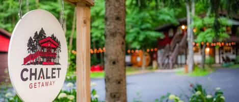 A sign for "CHALET GETAWAY" with a red chalet illustration, hanging on a wooden post.