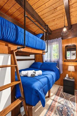 Une chambre avec un lit superposé, une échelle, une table de chevet, une lampe et un tapis à motifs.