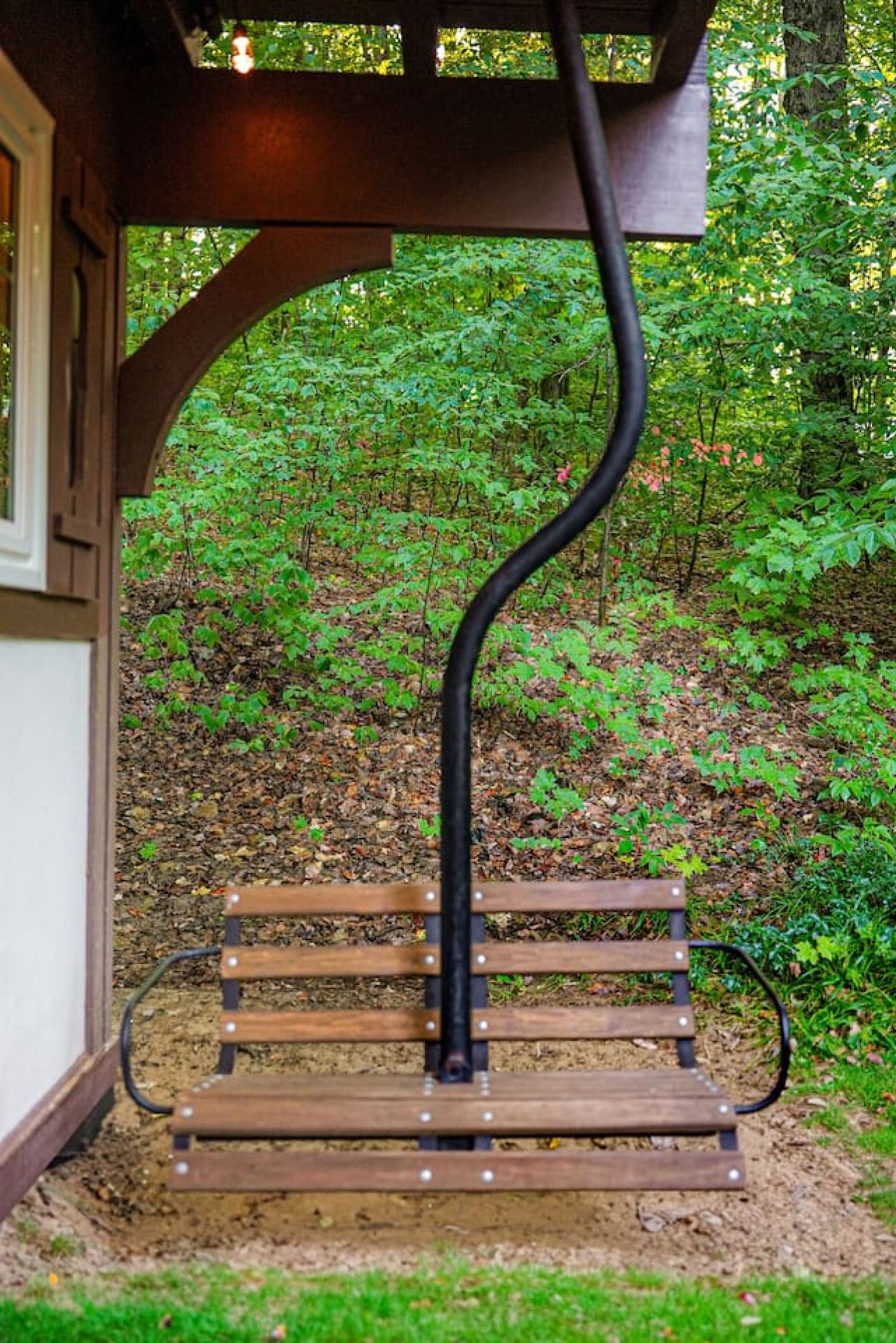 Un banco de madera con estructura de soporte metálica negra en un jardín.