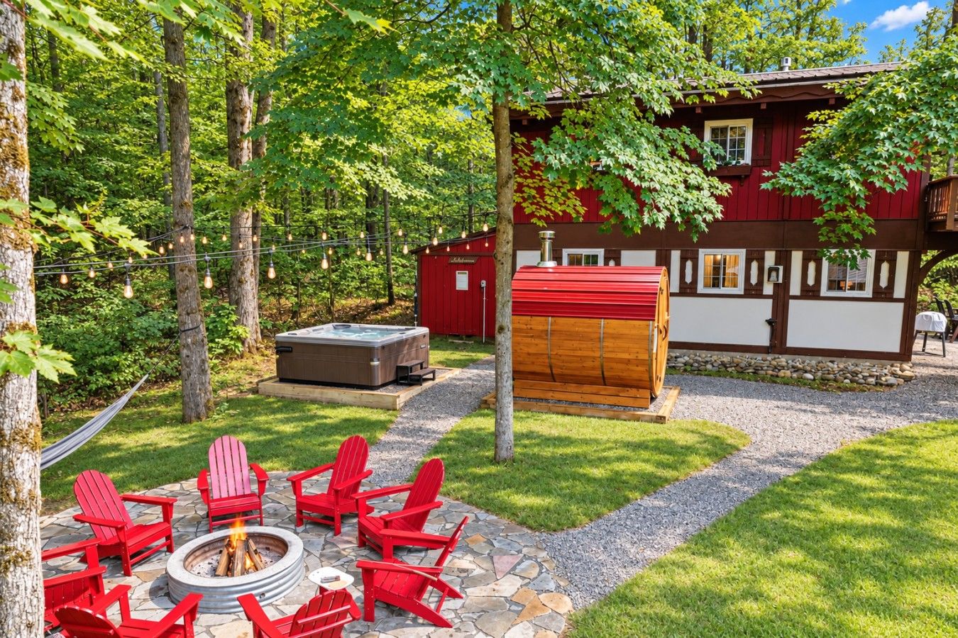 Un bain à remous en forme de tonneau en bois, une chaise Adirondack rouge et un foyer en pierre dans un jardin.
