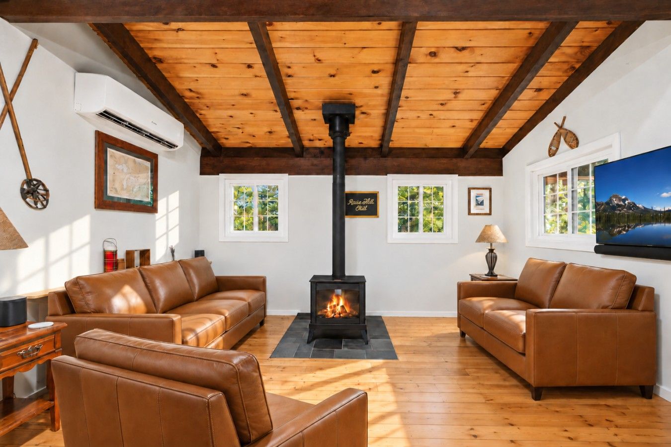 A cozy living room with two leather sofas, a fireplace, and a large window with a view of greenery.