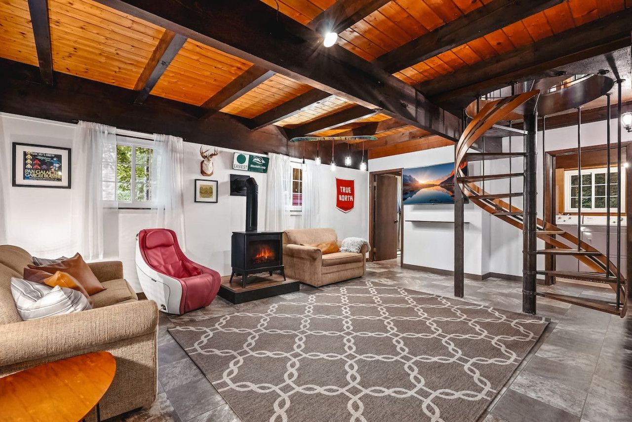 Ein gemütliches Wohnzimmer mit Kamin, einer Couch, einem roten Sessel und einem gemusterten Teppich.